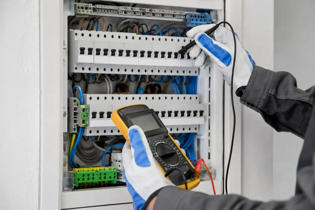 Elektrikár kontroluje a meria moderne označený elektrický rozvádzač